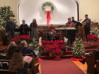 a group of people singing in a church with christmas decorations