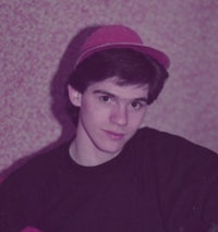 a young man wearing a hat in front of a pink wall