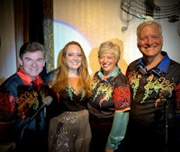 four people posing for a picture in front of a microphone
