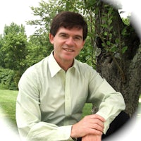 a man in a green shirt sitting under a tree