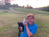 a man holding a can in front of a dog