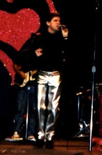 a man in silver pants singing into a microphone